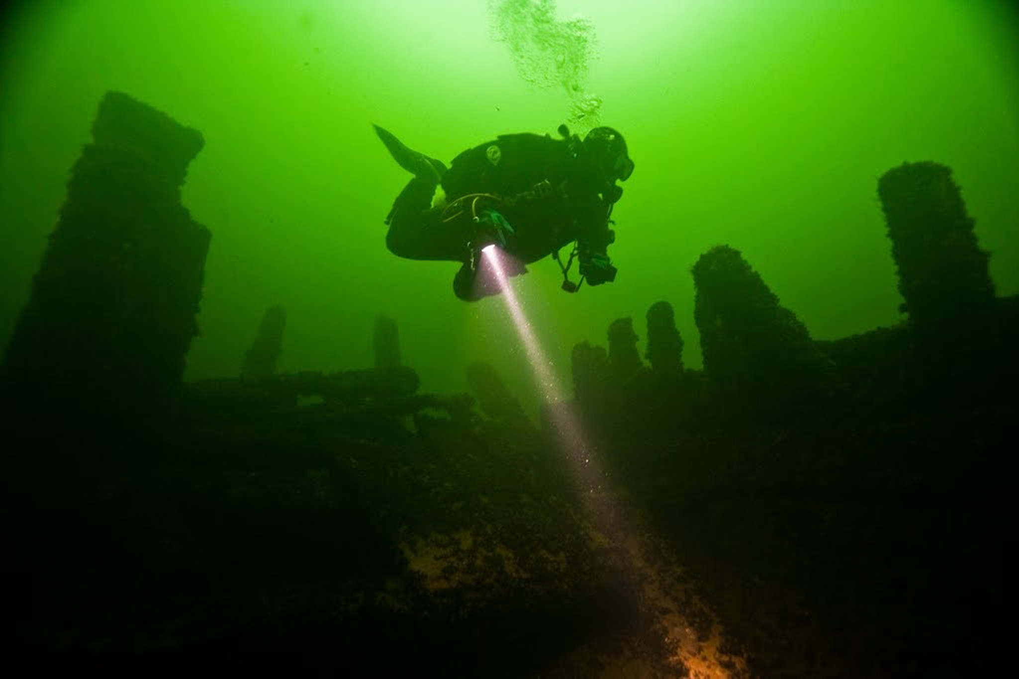En undervattensbild på en dykare med syrgastuber på ryggen.