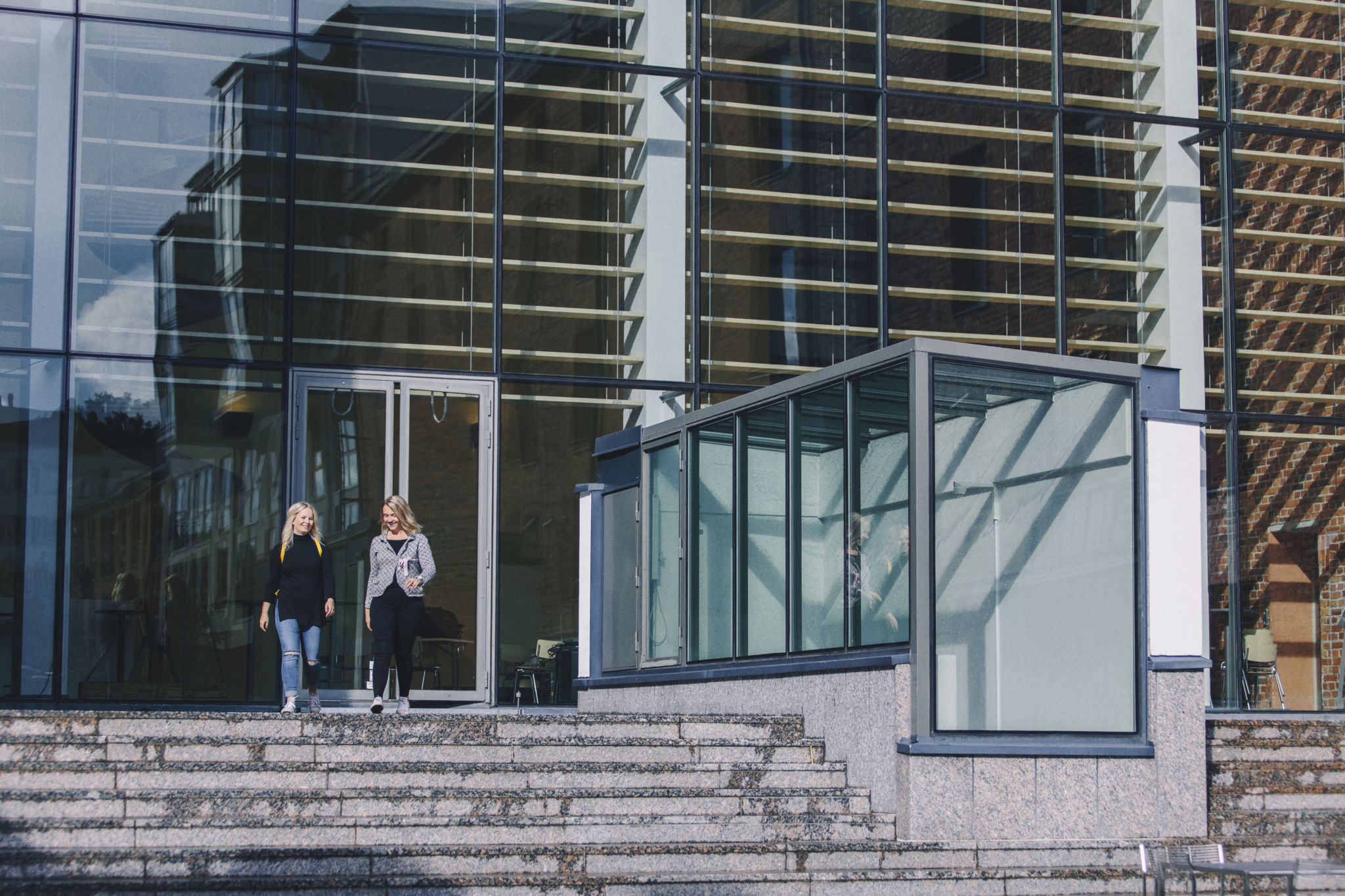 Två studerande på trappan till Academill.