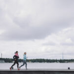 Två joggare som springer längs med stranden.