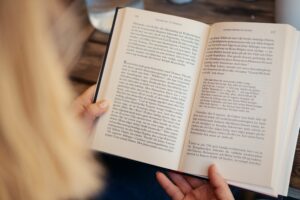 Närbild av blond kvinna som läser en bok i ett café