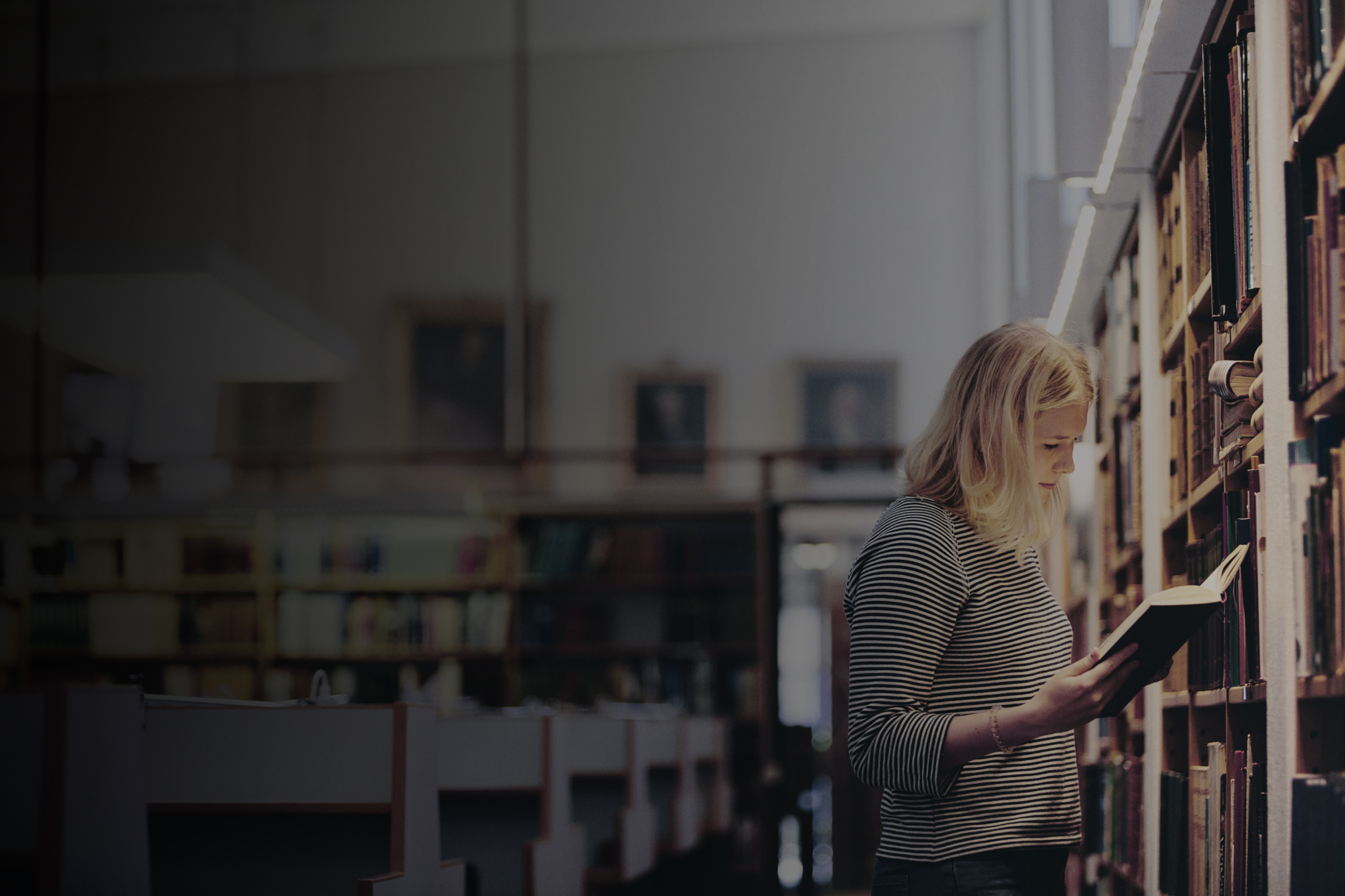 studerande läser bok vid hyllan