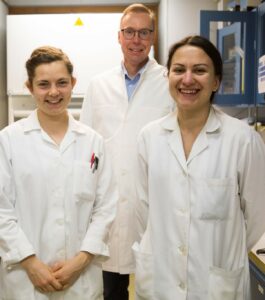 På bilden står tre personer i vita labbrockar, från vänster Emily Kemp, Johan Bobacka och Zhanna Boeva.