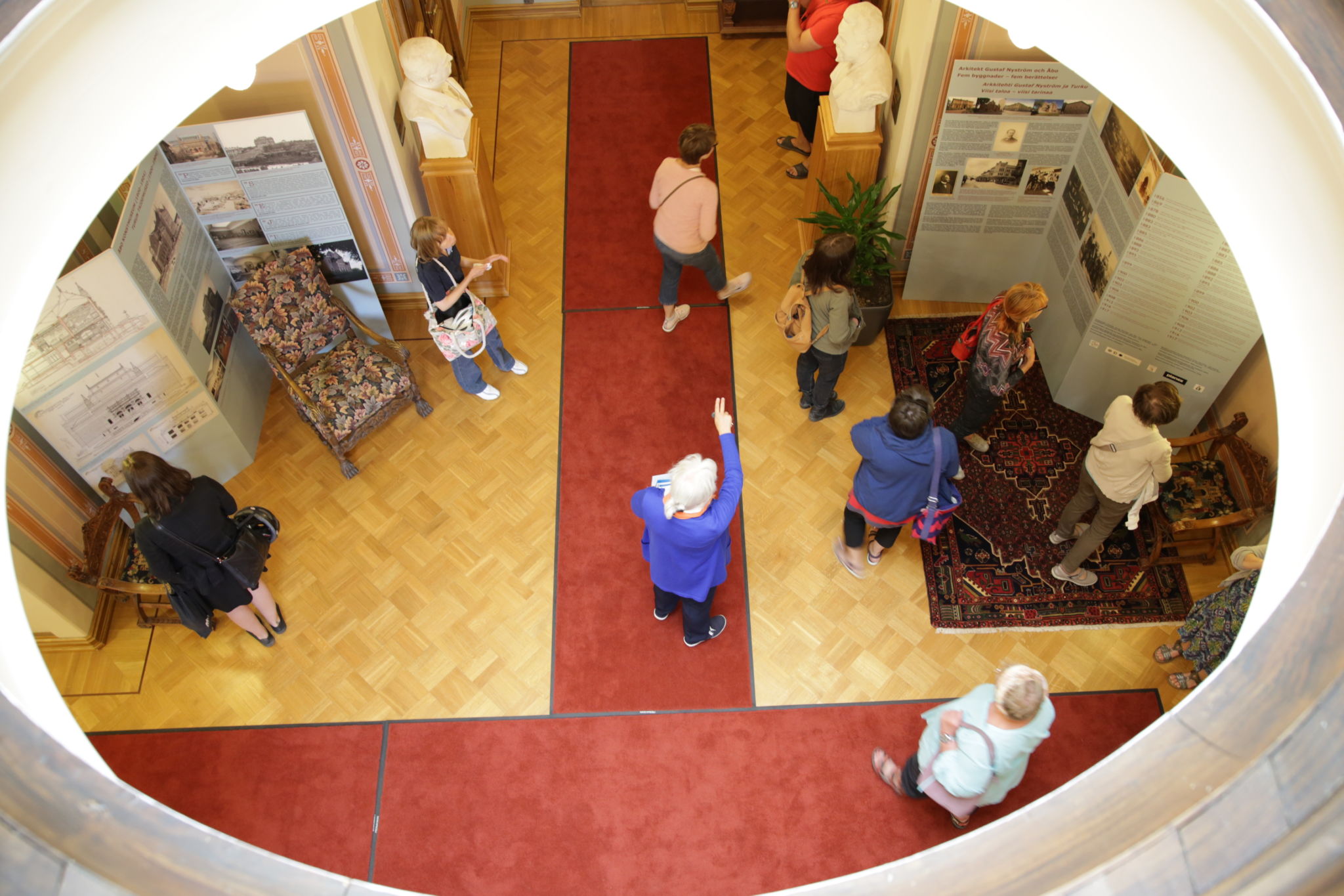 En grupp människor blir guidade inomhus, bilden tagen uppifrån