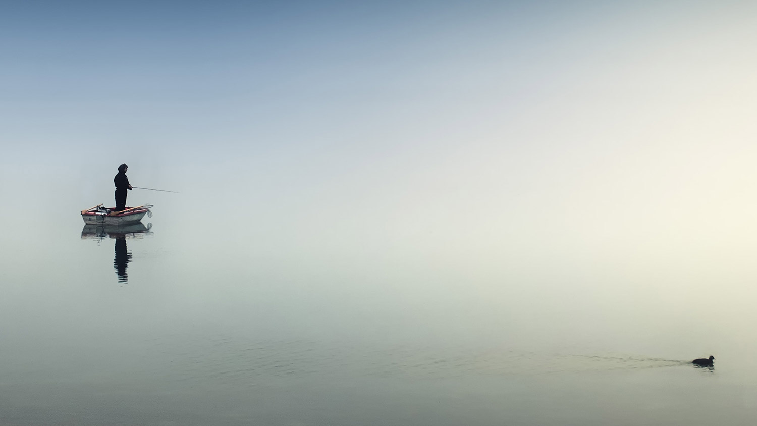 Fiskare på en båt i dimman